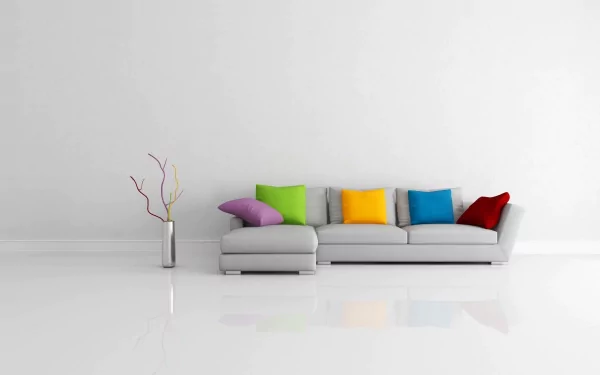 Artistic HD PC desktop wallpaper depicting modern furniture with a minimalist gray sectional sofa adorned with colorful cushions against a clean white wall.