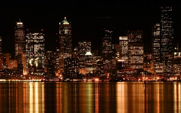 Seattle city skyline at night with illuminated buildings reflecting on the water, captured in a high-definition man-made scene for PC desktop wallpaper.