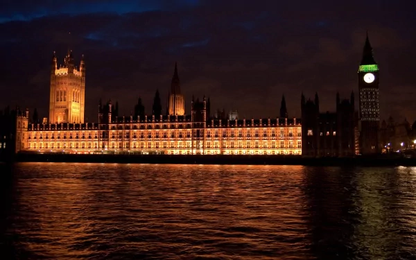 4K Ultra HD image of the illuminated Houses of Parliament and Big Ben reflected on the River Thames in London at night, showcasing iconic man-made architecture.