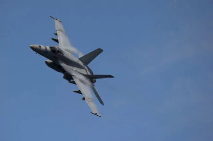 HD desktop wallpaper of a military Boeing F/A-18E/F Super Hornet aircraft flying against a clear blue sky.