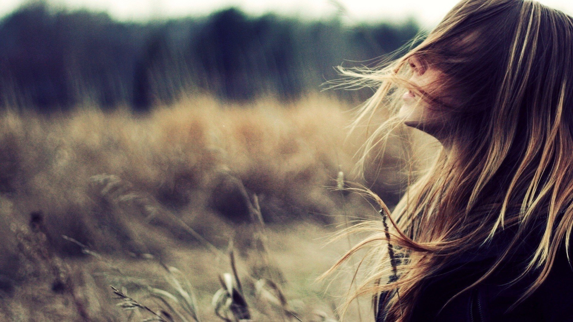 A woman with flowing hair stands in a field, embodying a serene mood. This high-definition image serves as a captivating desktop wallpaper and background.