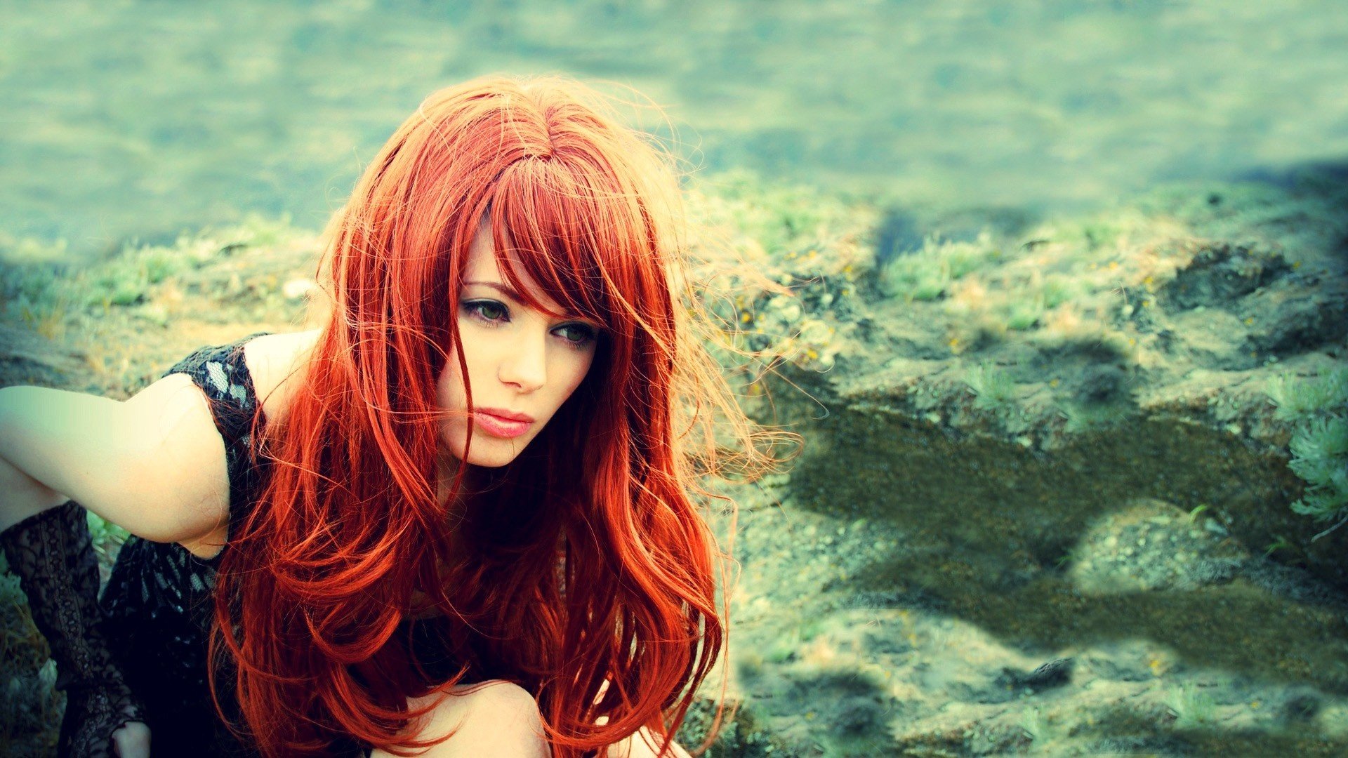 A beautiful redhead woman with flowing hair, captured in a moody, contemplative pose against a textured natural background, presented as an HD PC desktop wallpaper.
