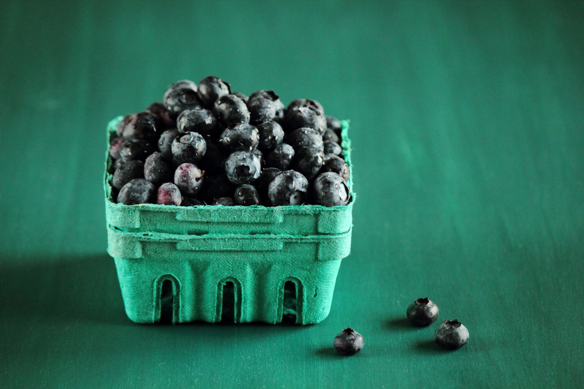 HD desktop wallpaper featuring a close-up of a teal carton filled with fresh blueberries on a matching teal background, highlighting food and blueberry themes.