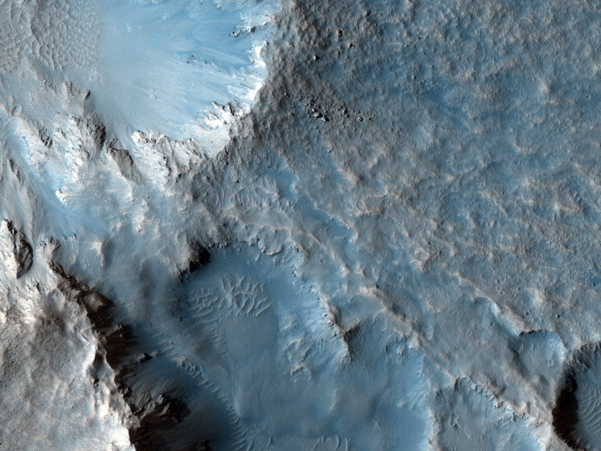 Sci-fi Mars 2K Quad HD PC desktop wallpaper showing icy blue-hued Martian surface—cratered basin, layered ridges and sharp cliffs under cold alien light.