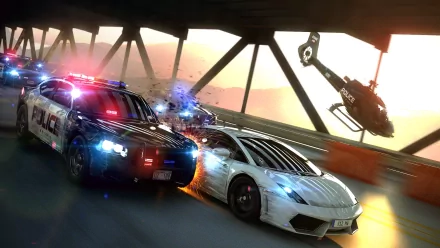High-definition desktop wallpaper featuring intense action from Need For Speed: Most Wanted, showcasing a police chase with a sleek sports car and helicopter under a dramatic sunset.