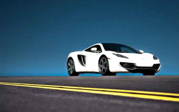 HD desktop wallpaper featuring a sleek white McLaren sports car on an empty road under a clear blue sky.