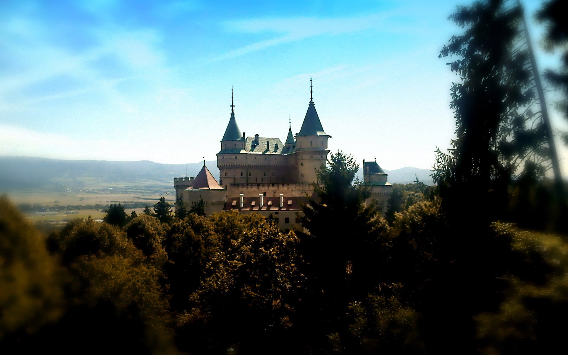 HD PC desktop wallpaper/background: Bojnice Castle, a man-made historic castle with spires rising above forested hills under a bright blue sky.