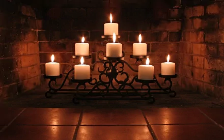 HD PC desktop wallpaper featuring a warm, atmospheric photograph of eight lit candles on an ornate metal candle holder against a rustic brick background.