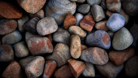 HD desktop wallpaper featuring a close-up of various smooth, multicolored stones arranged naturally, showcasing the textures and colors of nature.