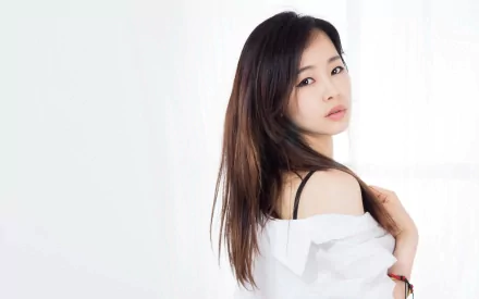 HD desktop wallpaper featuring an Asian woman with long hair and a white top, looking over her shoulder against a bright, minimalist background.