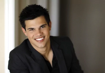 HD desktop wallpaper featuring Taylor Lautner, showcasing a smiling portrait of the celebrity in a stylish outfit with a soft background.