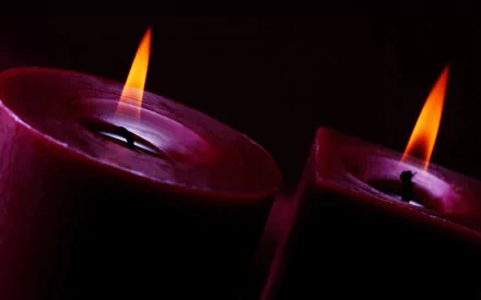 HD photography of two glowing candles with vibrant flames against a dark background, creating a warm and serene atmosphere for a PC desktop wallpaper.