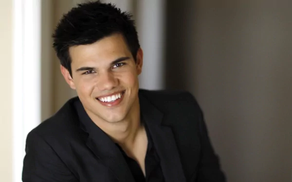 HD desktop wallpaper featuring Taylor Lautner, showcasing a smiling portrait of the celebrity in a stylish outfit with a soft background.