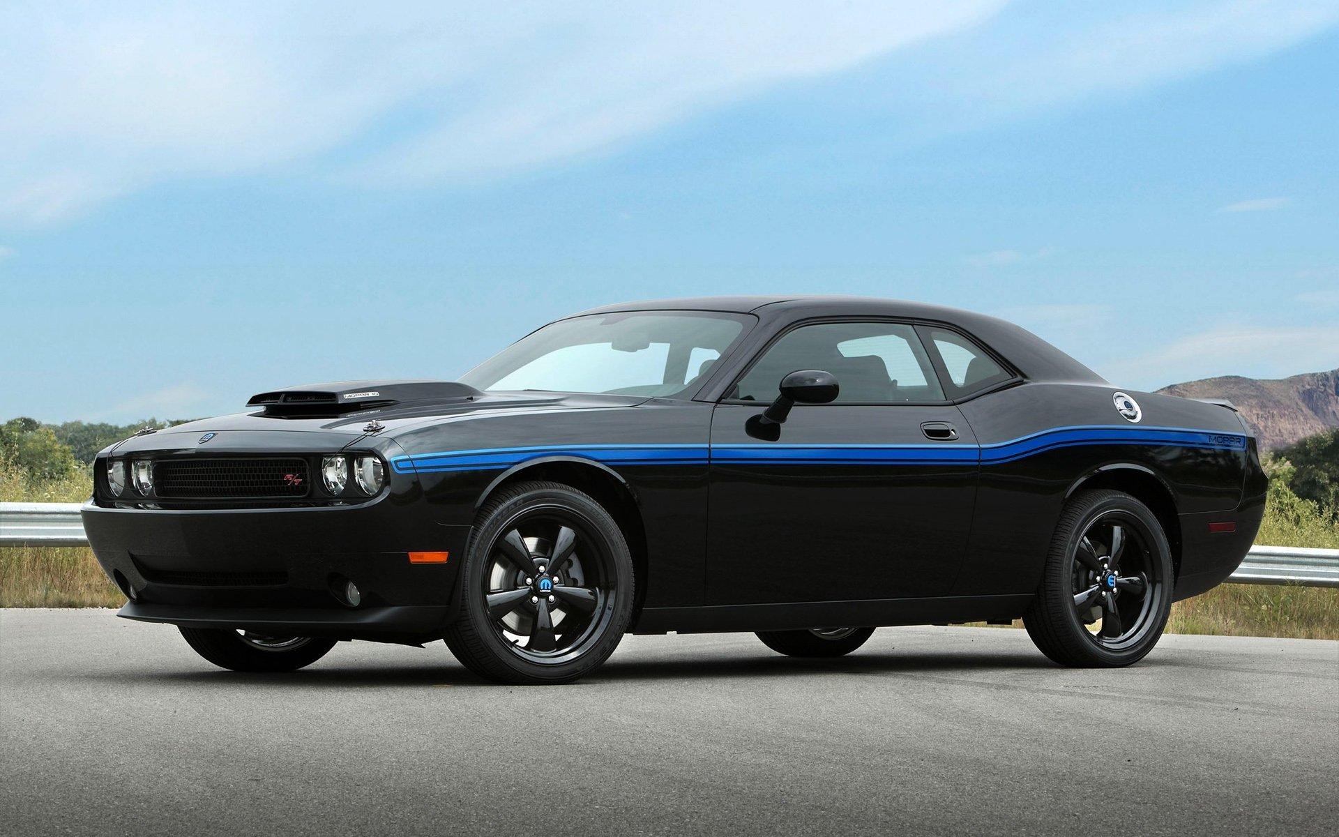 HD PC desktop wallpaper background showing a black Dodge Challenger with a blue racing stripe parked on a roadside under a bright sky.