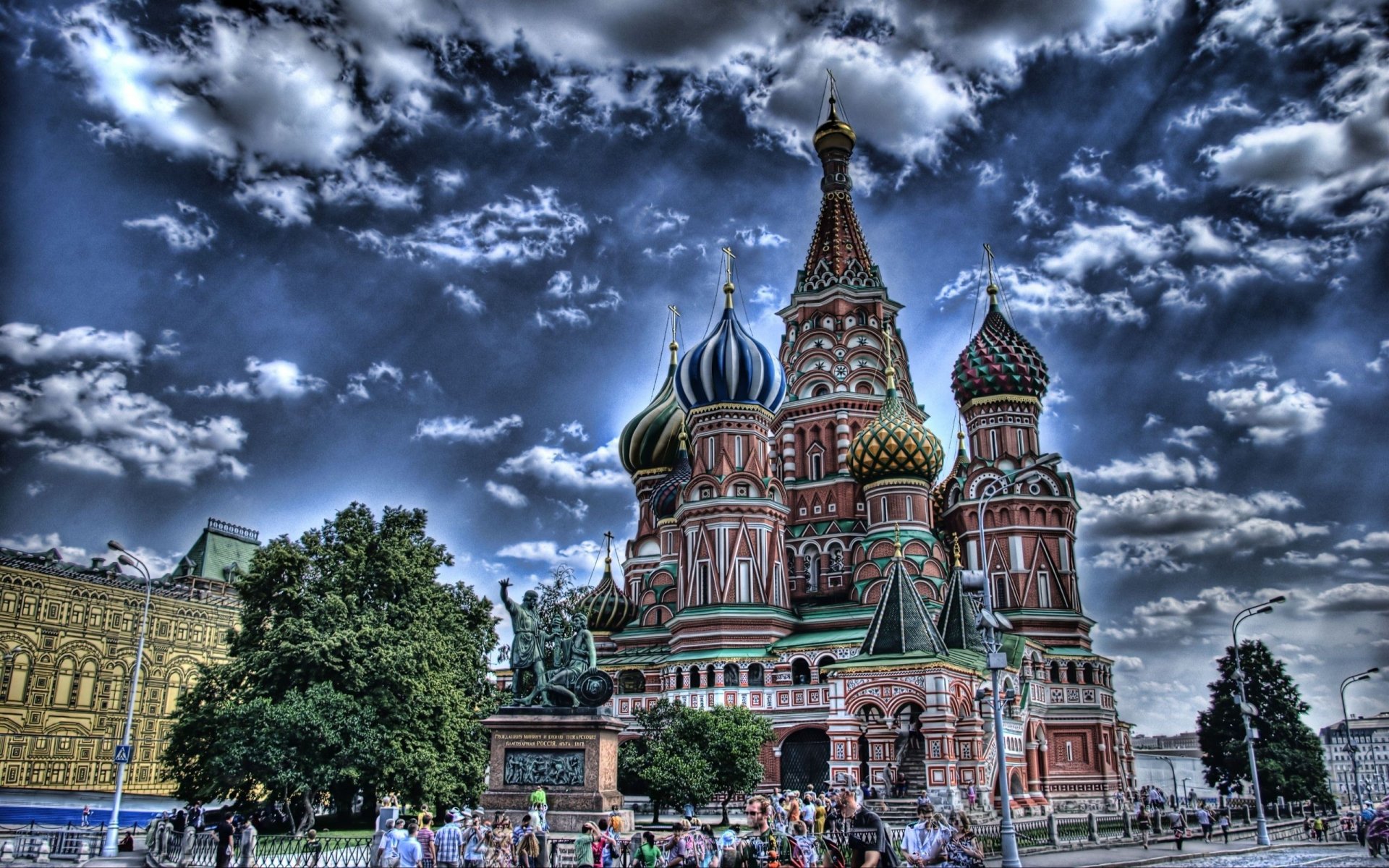 2K Quad HD desktop wallpaper of Saint Basil's Cathedral — colorful onion domes and ornate facades beneath dramatic clouds, a religious Moscow landmark.