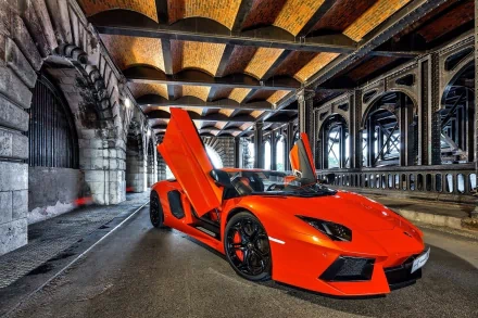 A striking Lamborghini Aventador in vivid orange, showcasing its iconic scissor doors, parked under an architectural bridge for a stunning HD desktop wallpaper.