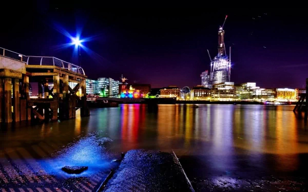 Nighttime view of London's illuminated skyline reflecting on the River Thames, captured as a vibrant man-made scene for an HD PC desktop wallpaper.