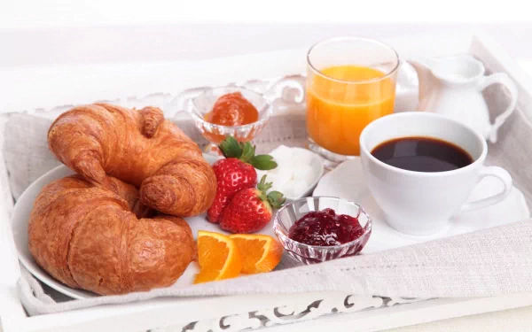 A breakfast still life featuring croissants, fresh strawberries, orange juice, coffee in a cup, and bowls of strawberry jam arranged on a tray, captured in HD for a desktop wallpaper.