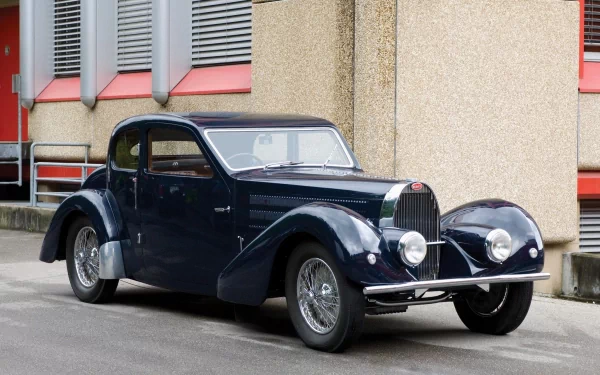 HD desktop wallpaper featuring a classic Bugatti Type 57 vehicle parked by a building, showcasing its vintage design and sleek dark blue exterior.