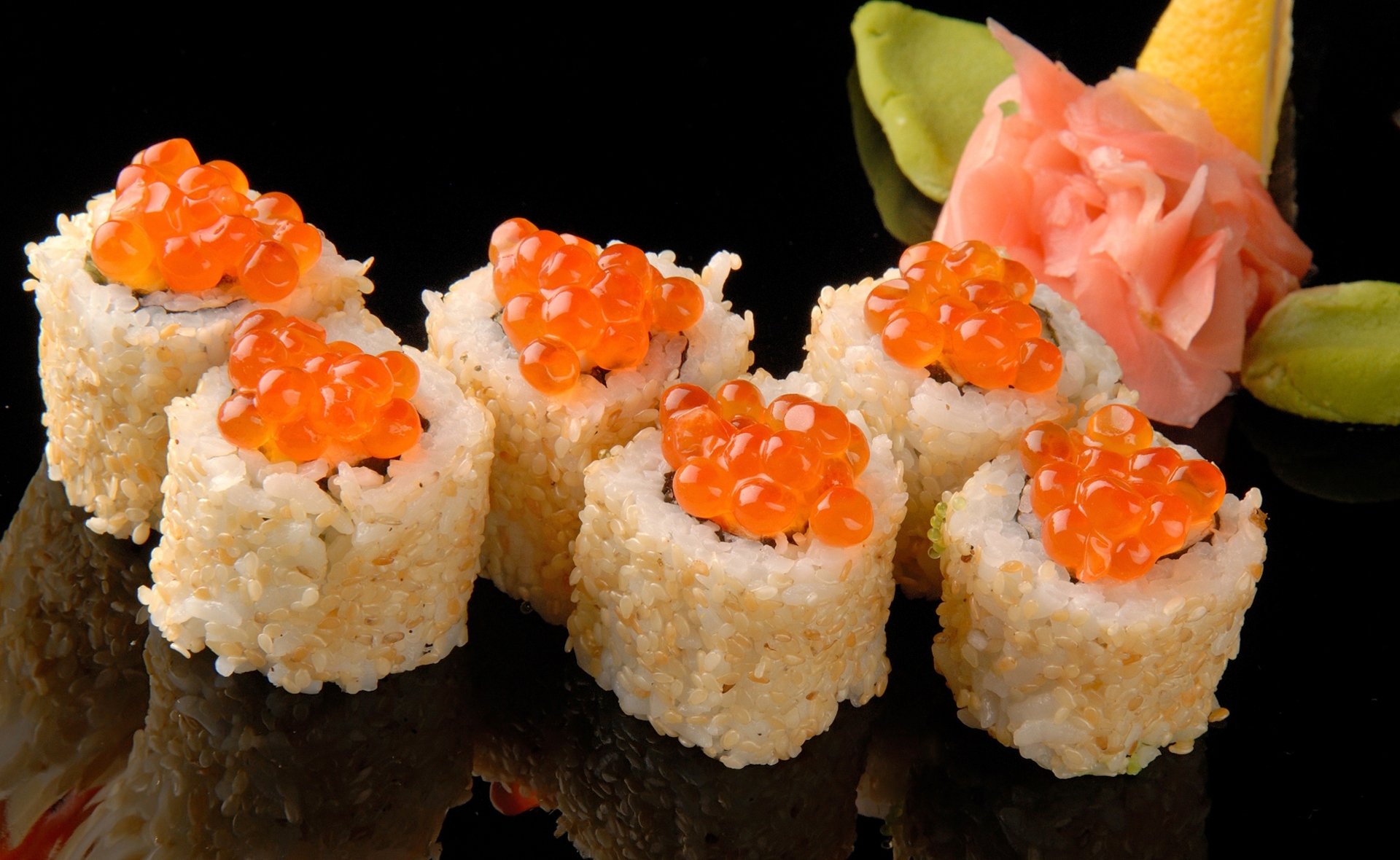 Close-up of sushi rolls topped with bright orange fish roe, presented with pickled ginger and wasabi on a reflective black surface, captured in 4K Ultra HD.