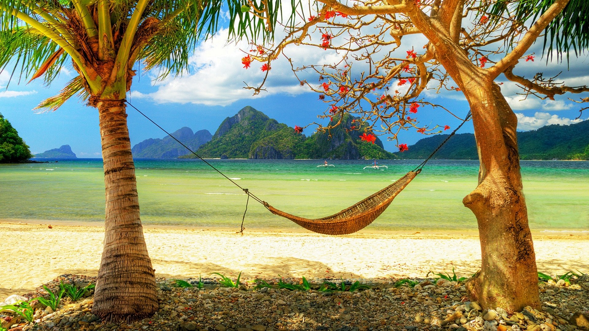 A serene tropical lagoon scene featuring palm trees, a hammock strung between two trees, and a picturesque beach backdrop with mountains in the distance. HD desktop wallpaper.