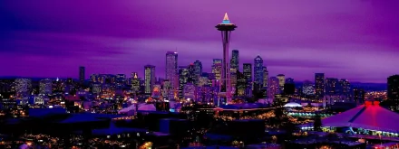 The image showcases the iconic Space Needle towering over Seattle's skyline, illuminated against a vivid purple sky, creating a stunning urban nightscape.