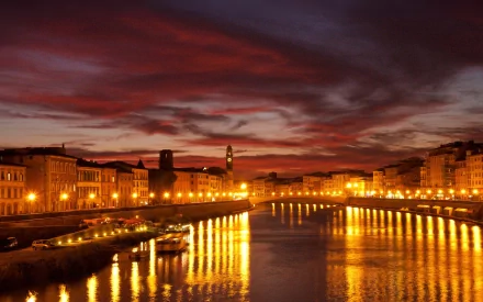 A serene night scene in Pisa, Italy, showcasing a canal lined with glowing lights reflecting on the water, flanked by charming houses and boats under a colorful sky.