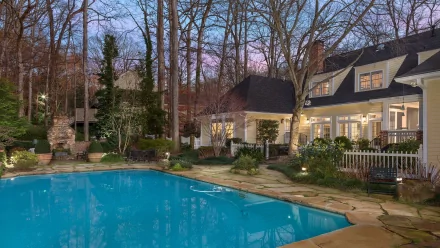 HD PC desktop wallpaper showing a serene man-made pool surrounded by trees and a warmly lit house at dusk.