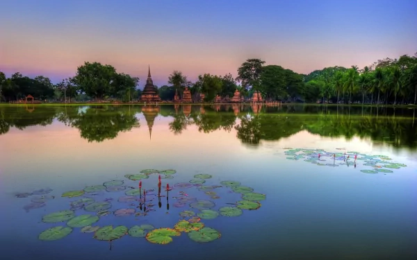 HD desktop wallpaper showcasing a serene Thailand park landscape at sunset, with ancient temple silhouettes reflected in calm water surrounded by lush greenery.