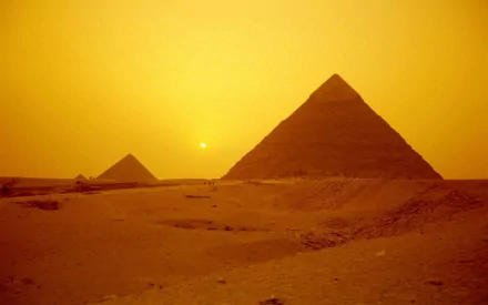HD desktop wallpaper featuring man-made pyramids silhouetted against a golden sunset in a desert landscape.