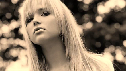 HD desktop wallpaper of Arielle Kebbel, showcasing a woman with long, straight blonde hair, gazing at the camera with a blurred, bokeh background.