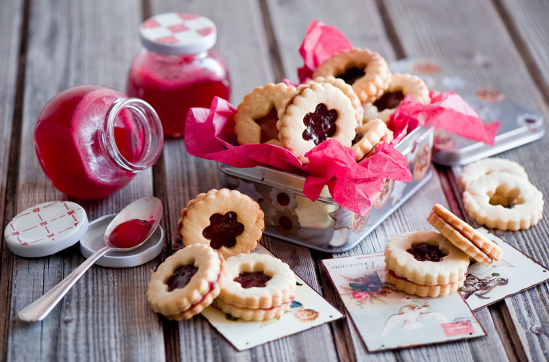 A delightful array of cookies in a decorative basket, surrounded by colorful jars and vintage postcards, captured in high definition for a beautiful desktop wallpaper.