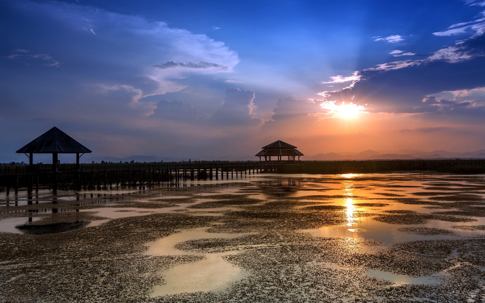 HD desktop wallpaper featuring a man-made pier extending over reflective water under a dramatic sunset sky.
