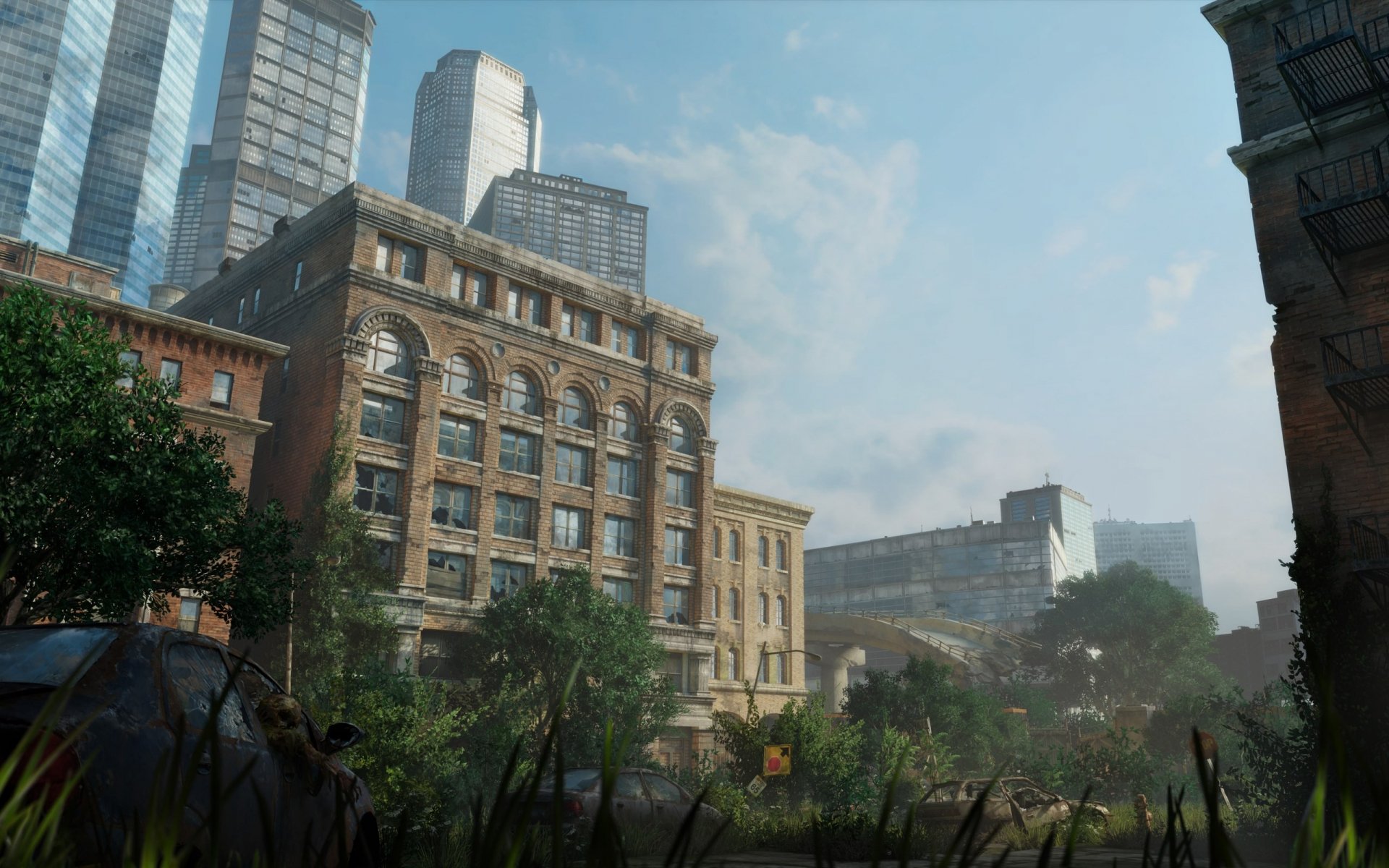HD PC desktop wallpaper from the video game The Last of Us, depicting an overgrown urban landscape with decaying buildings under a clear sky.