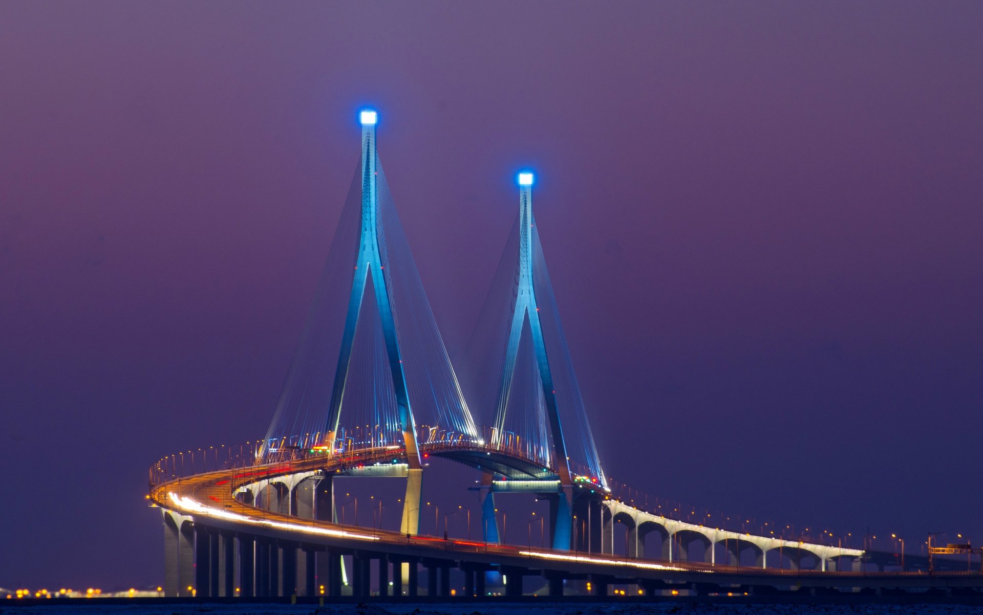HD desktop wallpaper showcasing a man-made illuminated cable-stayed bridge glowing against a deep purple twilight sky.