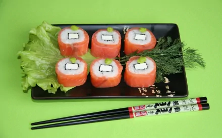 HD desktop wallpaper featuring six pieces of sushi rolls with salmon, cream cheese, and cucumber on a black plate, accompanied by chopsticks on a light green background.
