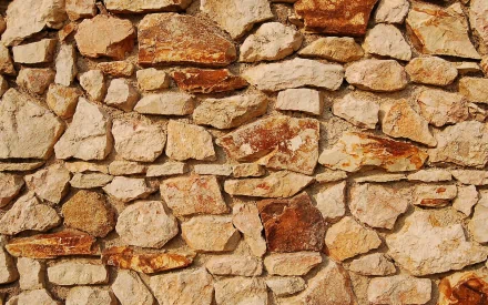 A textured stone wall composed of various sizes and colors of rocks, creating a natural yet man-made appearance, serving as an engaging HD PC desktop wallpaper.