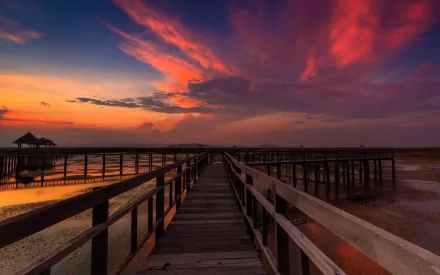HD desktop wallpaper featuring a man-made wooden pier extending into calm waters under a vibrant, colorful sunset sky.