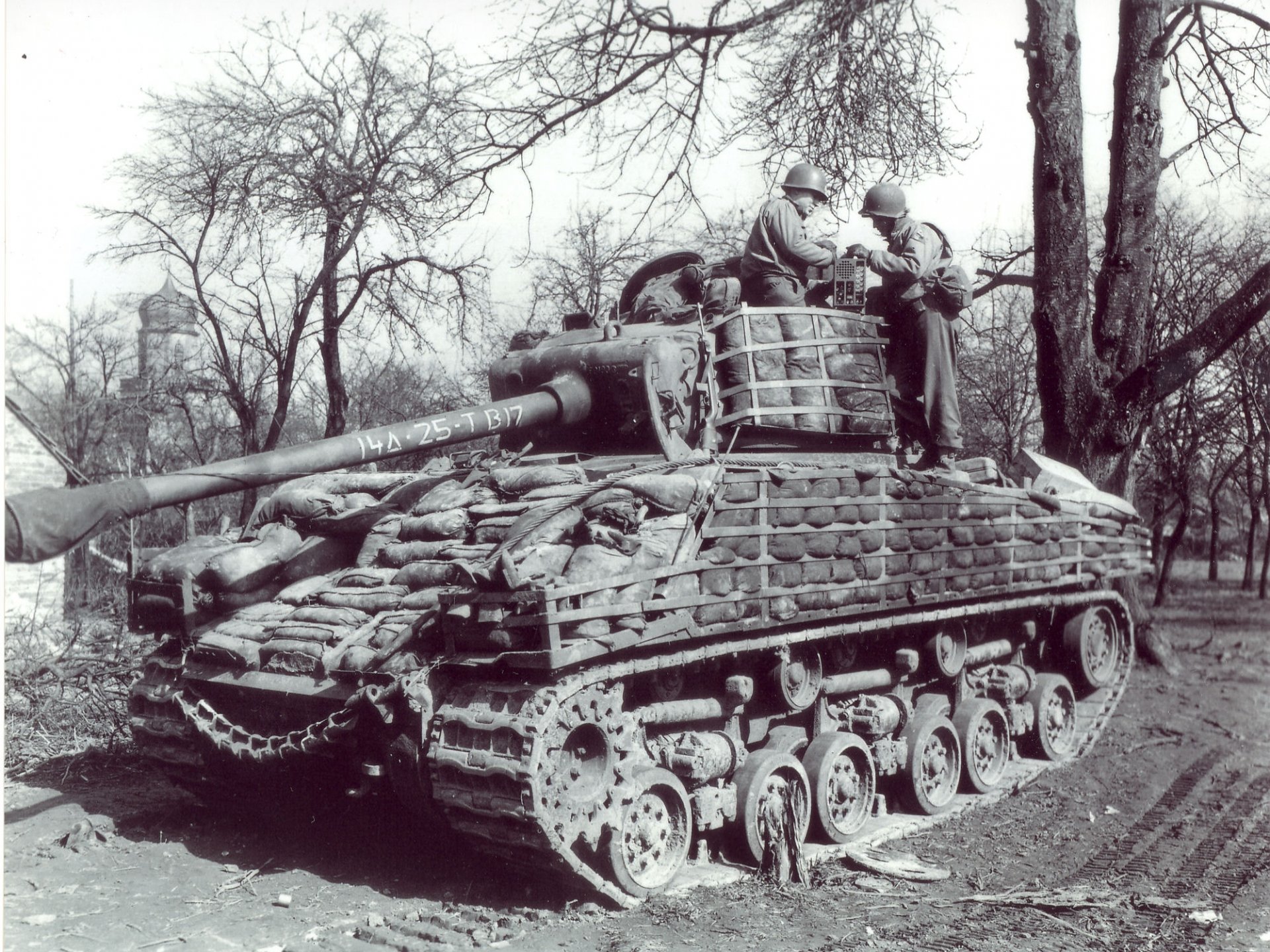 Black and white HD desktop wallpaper of a military M4 Sherman tank with soldiers standing on it in a wooded area.
