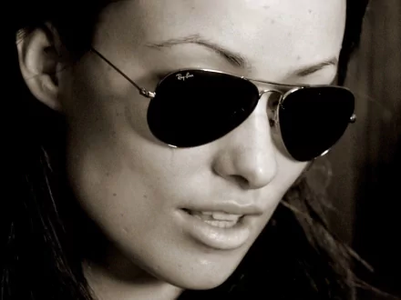 HD PC desktop wallpaper: sepia close-up portrait of a woman in aviator sunglasses, intense gaze and slightly parted lips, high-contrast cinematic background.