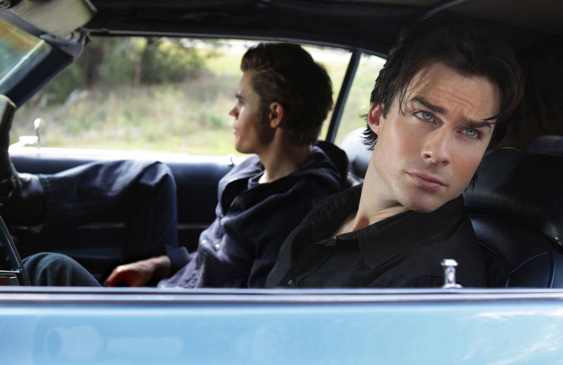 A striking HD wallpaper from The Vampire Diaries, featuring two characters in a classic car, capturing a moment of contemplation and connection amid a scenic backdrop.