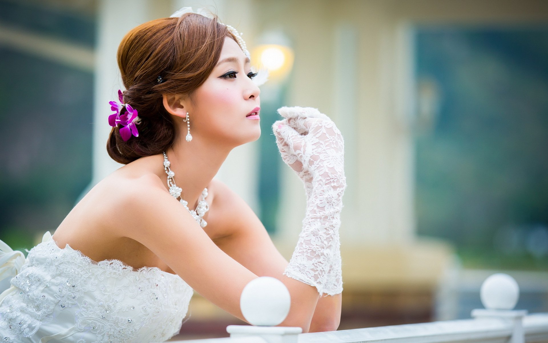 HD desktop wallpaper featuring an Asian woman in a white lace dress and gloves, with a purple flower in her hair, posing thoughtfully outdoors.