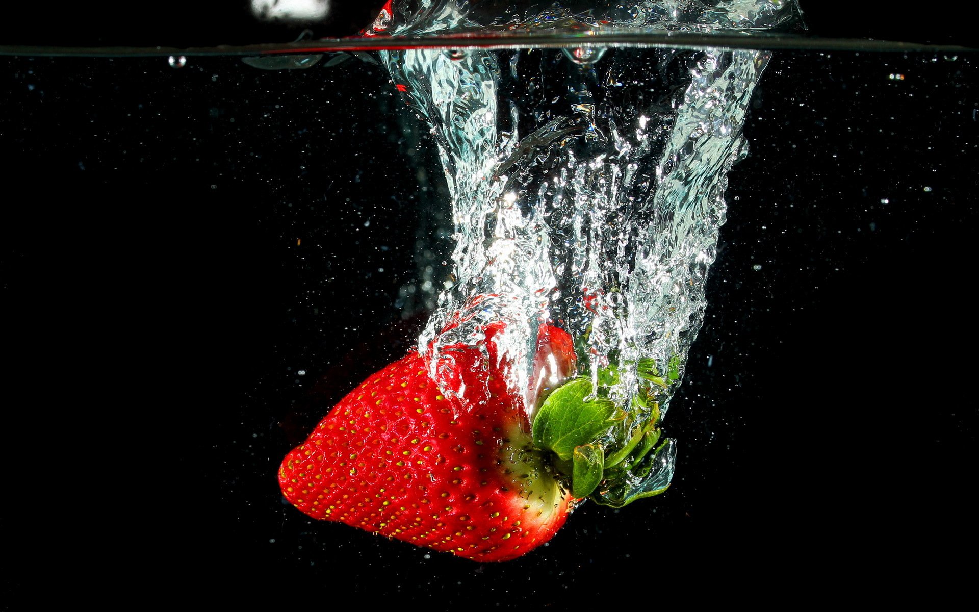 HD PC desktop wallpaper featuring a fresh strawberry splashing underwater, highlighting vibrant red and green colors against a dark background.