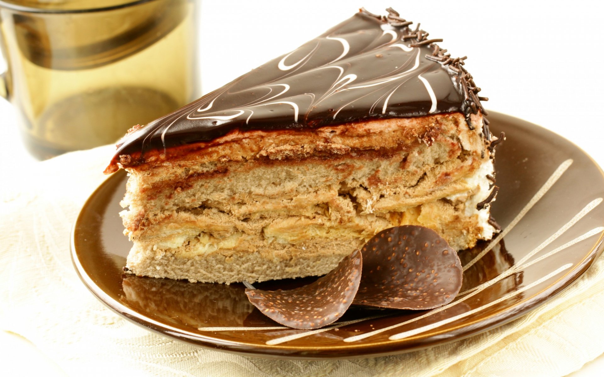HD PC desktop wallpaper featuring a close-up of a layered cake slice with chocolate glaze and decorative chocolate pieces on a white plate.