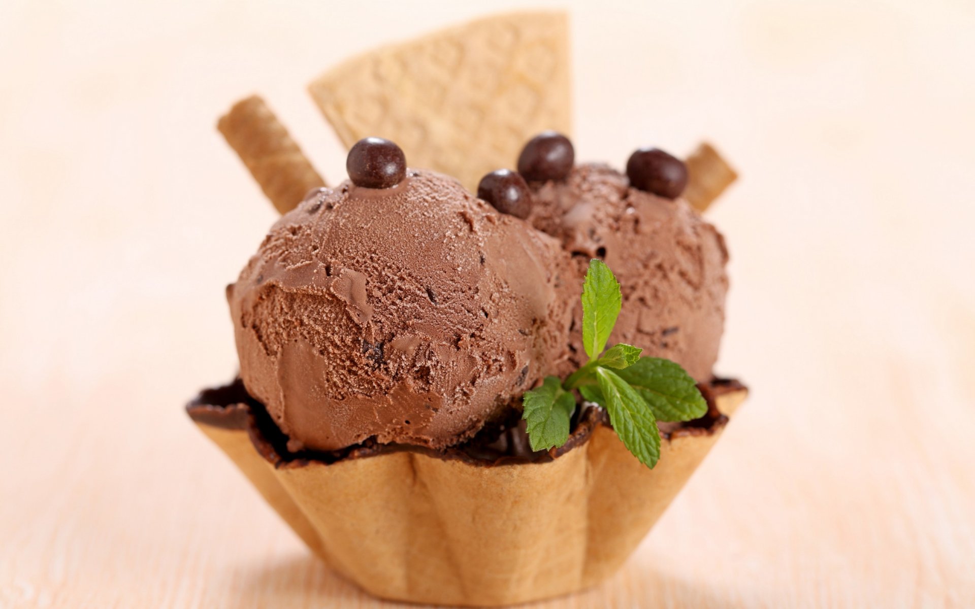 HD desktop wallpaper featuring two scoops of chocolate ice cream in a waffle cup, garnished with chocolate pearls, wafer sticks, and a fresh mint sprig.