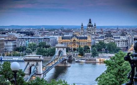 HD desktop wallpaper showcasing the man-made Chain Bridge spanning a river, with historic buildings and a cityscape in the background under a blue sky.