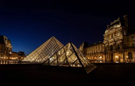 Night view of the illuminated Louvre Museum and its glass pyramids in Paris, captured as an HD desktop wallpaper background.