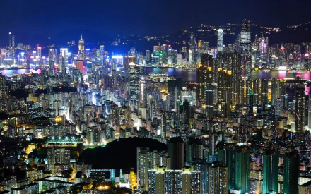 Nighttime view of Hong Kong's vibrant cityscape with illuminated skyscrapers and residential buildings, captured as a high-definition man-made desktop wallpaper.