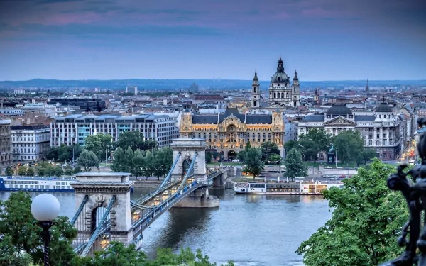 HD desktop wallpaper showcasing the man-made Chain Bridge spanning a river, with historic buildings and a cityscape in the background under a blue sky.