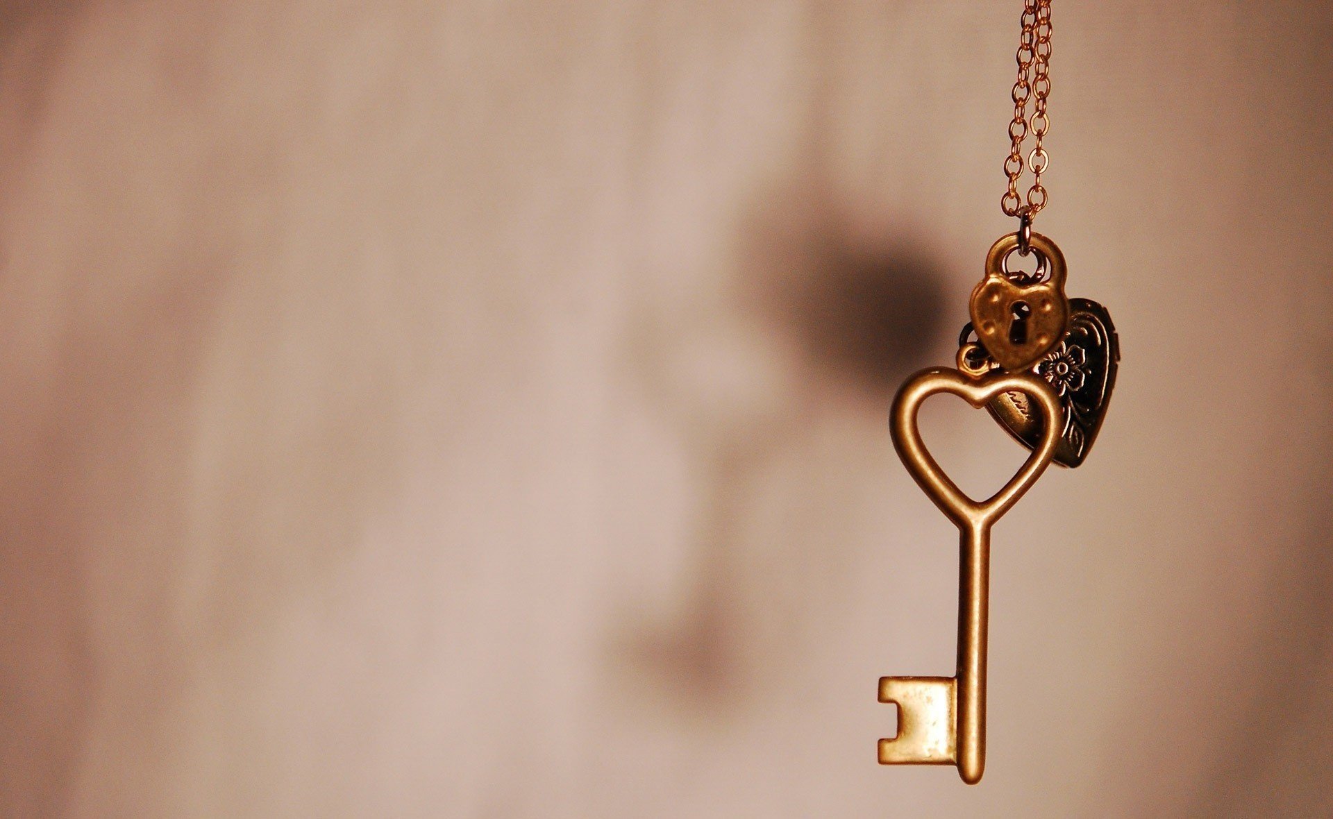 HD desktop wallpaper featuring a close-up of a vintage heart-shaped key pendant hanging against a soft, blurred background, capturing a theme of love and photography.